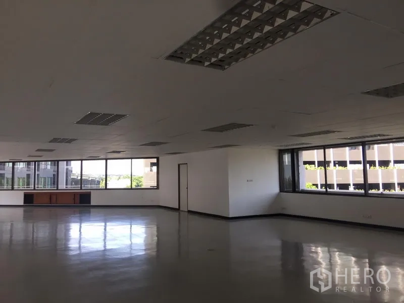 Office Space for rent in Bang Kapi, Bangkok - Corner section of office with wraparound windows and natural light overlooking nearby buildings.