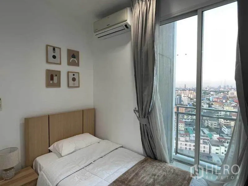 Condominium for rent or sale in Watthana, Bangkok - Cozy bedroom with city-view floor-to-ceiling window and balcony access.
