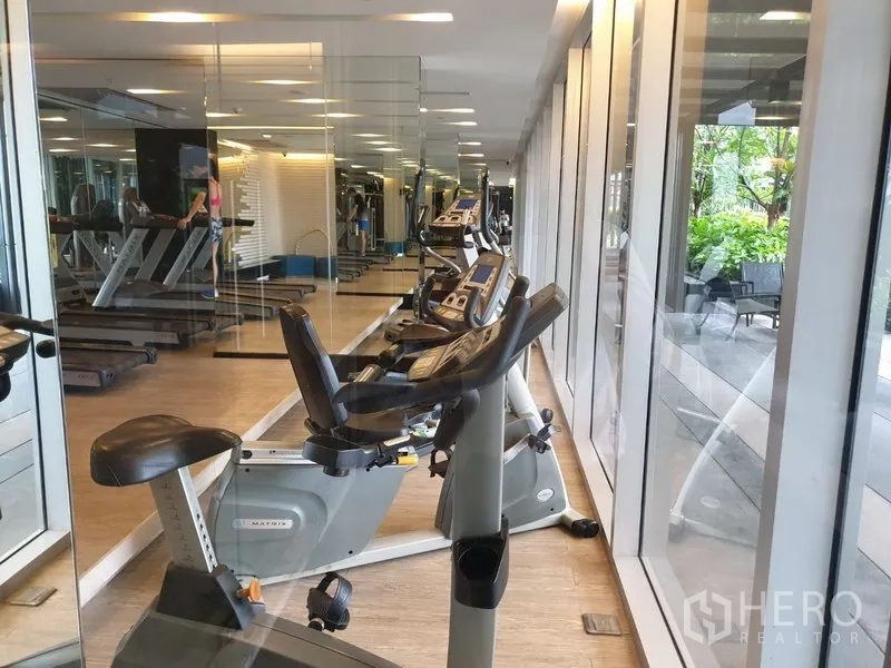 Condominium for rent in Watthana, Bangkok - Well-equipped fitness room with cardio machines and garden outlook.