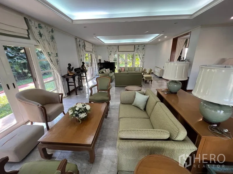 Detached House for rent in Bang Phli, Samut Prakan - Spacious living room with large windows, tray ceiling lighting, and garden views.