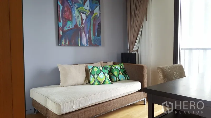 Condominium for rent in Sathon, Bangkok - Cozy third bedroom or study with daybed, colorful artwork, and floor-to-ceiling glass.