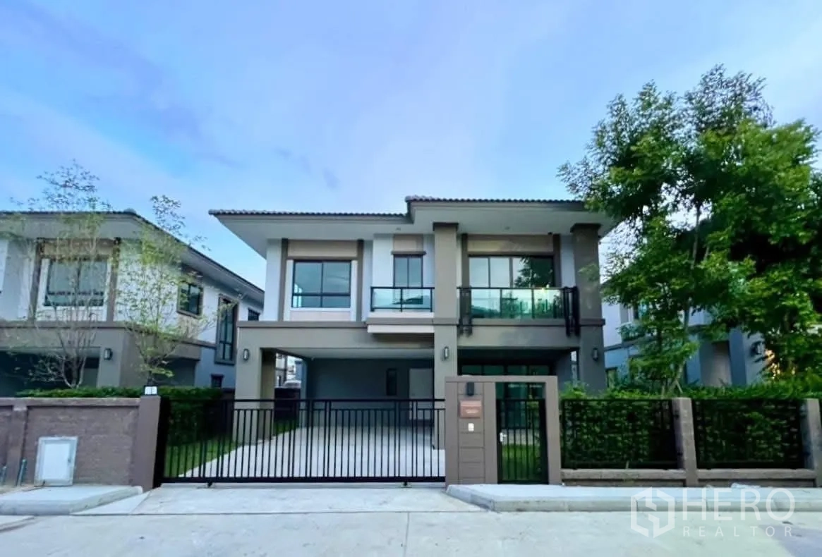 Detached House for rent in Bang Phli, Samut Prakan - Modern two-storey detached house facade with gated driveway, balcony and landscaped hedges in Bang Phli.