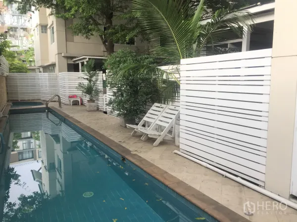 Detached House for rent in Watthana, Bangkok - Leafy compound swimming pool with sun loungers and privacy fence.