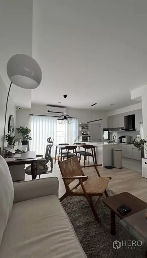 Townhouse for rent in Bang Phli, Samut Prakan - Wide view of open living space featuring kitchen island, dining set, work desk and sheer curtains.
