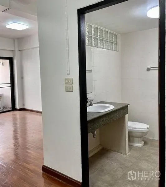 สำนักงานที่บ้าน ให้เช่าในKhlong Toei, Bangkok - ทางเข้าห้องน้ำจากห้องพื้นไม้ เห็นอ่างล้างหน้า โถสุขภัณฑ์ และบล็อกแก้ว