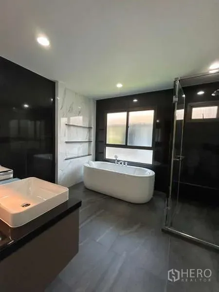 独立式住宅 出租在Bang Kapi, Bangkok - 现代浴室，独立浴缸、玻璃淋浴、大窗与黑白墙面。