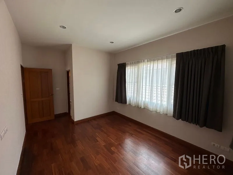 Detached House for rent or sale in Pak Kret, Nonthaburi - Guest bedroom with window, curtains and wood floor.