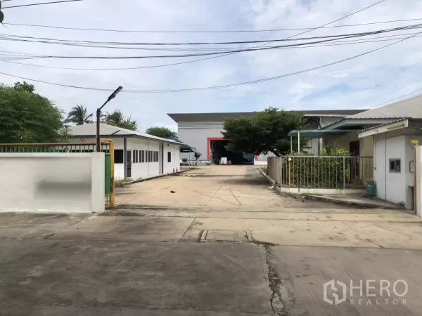 Factory for rent in Mueang Samut Prakan, Samut Prakan - Gated driveway leading to large warehouse and office buildings