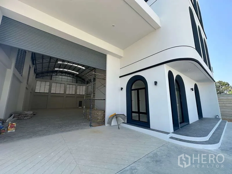 โรงงาน ขายในLam Luk Ka, Pathum Thani - โซนขนถ่ายสินค้าและทางเข้าออฟฟิศ ข้างประตูม้วนขนาดใหญ่ของโกดัง