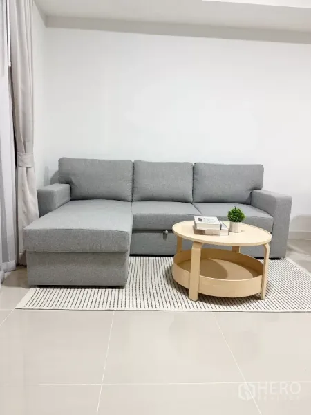 Townhouse for rent in Bang Phli, Samut Prakan - Cozy living room featuring a gray L-shaped sofa and round wooden coffee table.