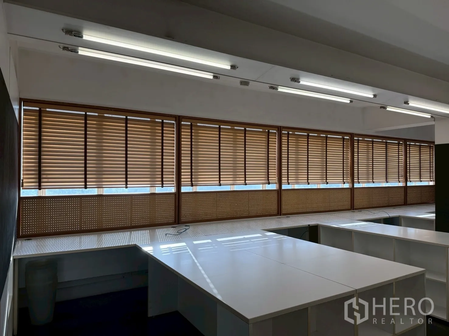 Office Space for rent in Huai Khwang, Bangkok - Large windows with wooden blinds above corner work desks in a modern office space.