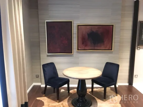 คอนโด ให้เช่าในWatthana, Bangkok - ภาพใกล้มุมทานอาหาร โต๊ะกลมไม้ เก้าอี้สีน้ำเงินสองตัว และงานศิลป์บนผนัง พื้นไม้