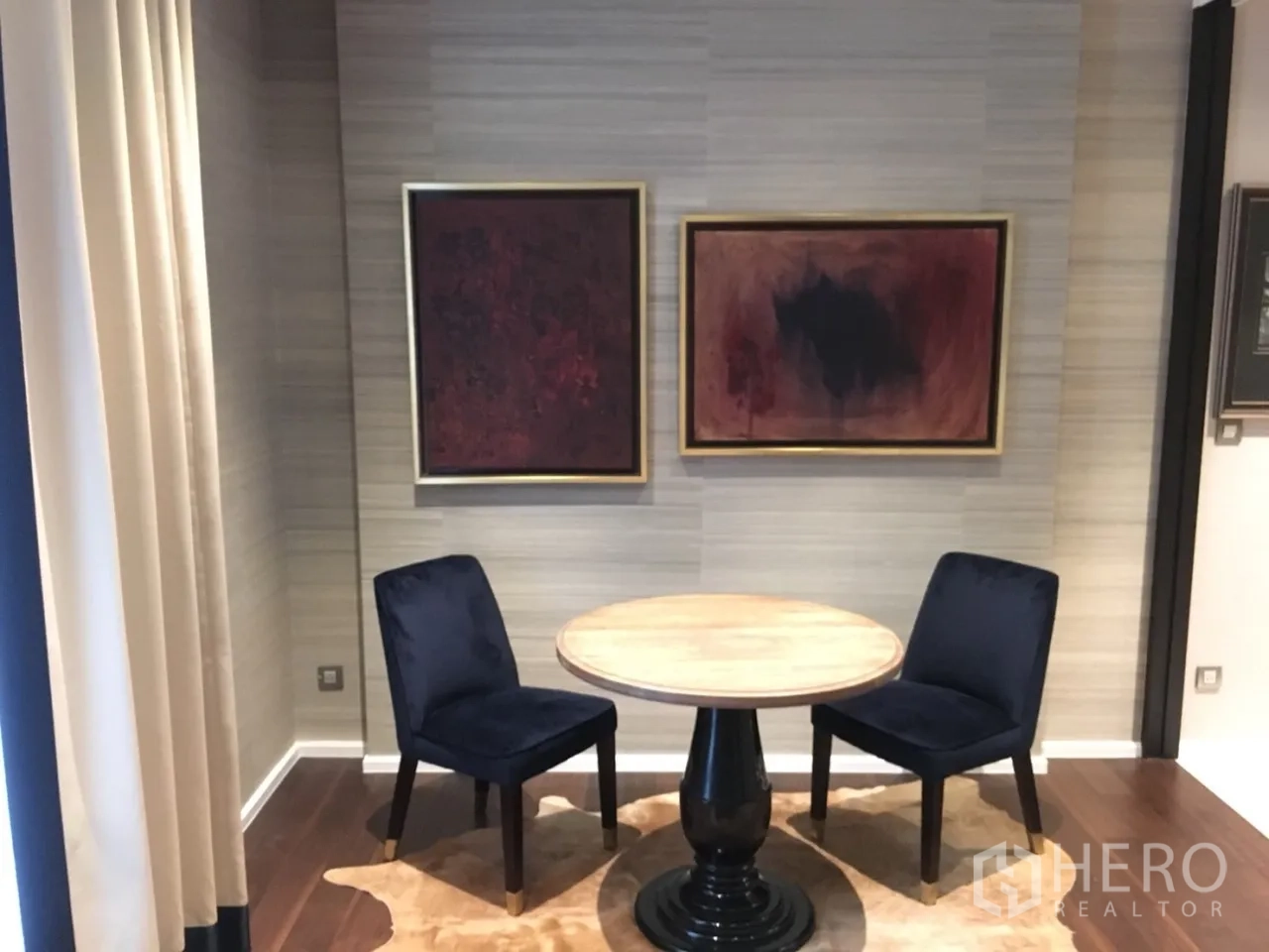 คอนโด ให้เช่าในWatthana, Bangkok - ภาพใกล้มุมทานอาหาร โต๊ะกลมไม้ เก้าอี้สีน้ำเงินสองตัว และงานศิลป์บนผนัง พื้นไม้