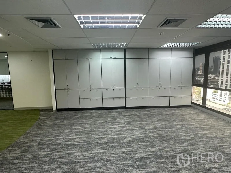 Office Space for rent in Khlong Toei, Bangkok - Wall of lockable storage cabinets beside corner windows in the office area.