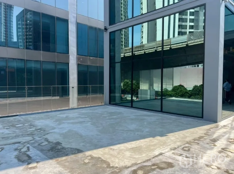 Retail Space for rent in Khlong Toei, Bangkok - Modern glass-façade retail building with a spacious outdoor forecourt on a sunny day.