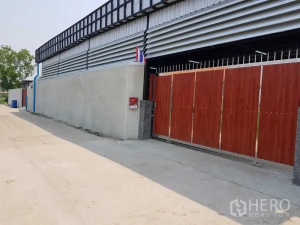 货栈 出售在Lam Luk Ka, Pathum Thani - 仓库正门视角，木纹滑动门与金属覆面，临一条安静通道。