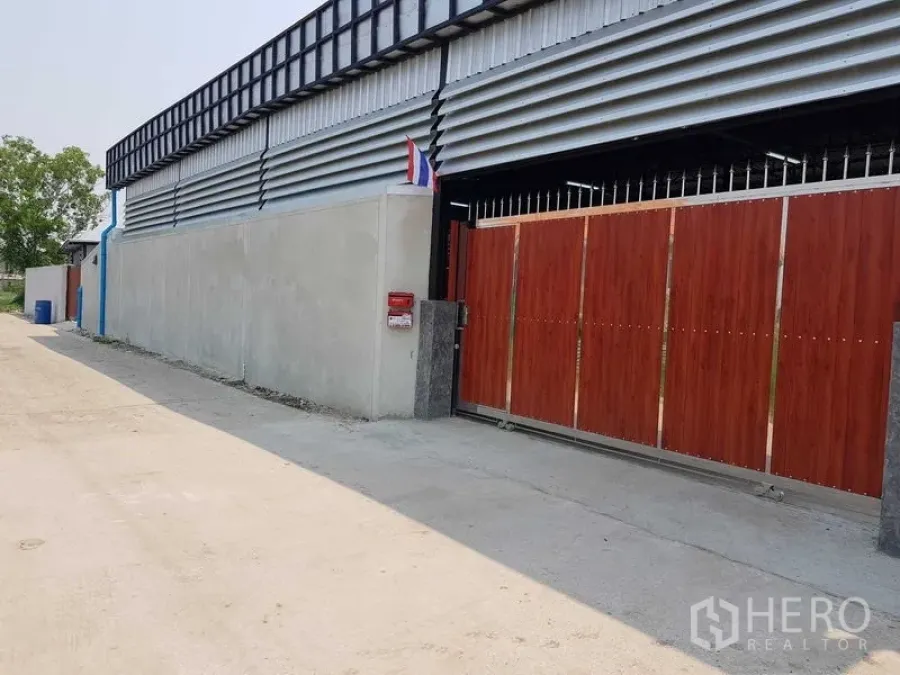 货栈 出售在Lam Luk Ka, Pathum Thani - 仓库正门视角，木纹滑动门与金属覆面，临一条安静通道。