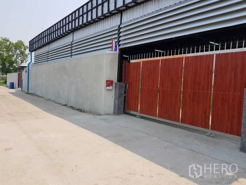 货栈 出售在Lam Luk Ka, Pathum Thani - 仓库正门视角，木纹滑动门与金属覆面，临一条安静通道。