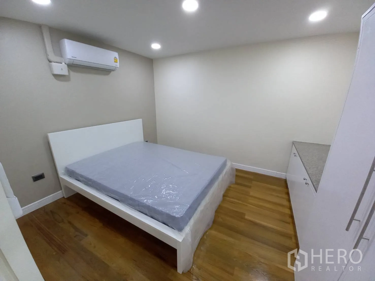 公寓 出租在Khlong Toei, Bangkok - 卧室内挂壁式空调，白色床架与内置储物柜，木地板。