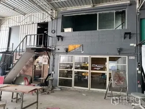 货栈 出售在Phra Samut Chedi, Samut Prakan - 仓库内带玻璃立面的夹层办公室，金属楼梯与作业区。