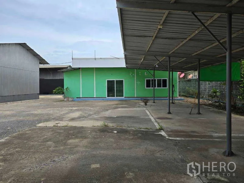 Warehouse for rent in Khlong Sam Wa, Bangkok - Single-storey green office with sliding glass doors and covered parking bays.