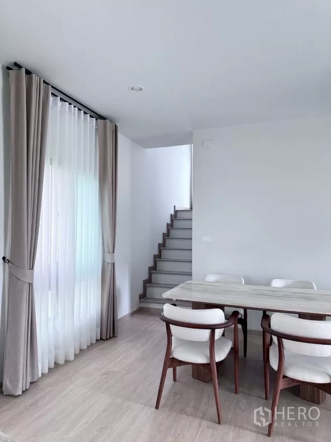 บ้าน ให้เช่าในLat Krabang, Bangkok - พื้นที่รับประทานอาหารติดโถงบันได พร้อมหน้าต่างบานใหญ่และผ้าม่านโทนอบอุ่น