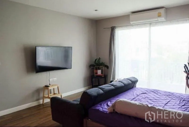Detached House for rent or sale in Khlong Sam Wa, Bangkok - Master bedroom featuring wall-mounted TV, air conditioning and sliding doors to a balcony.
