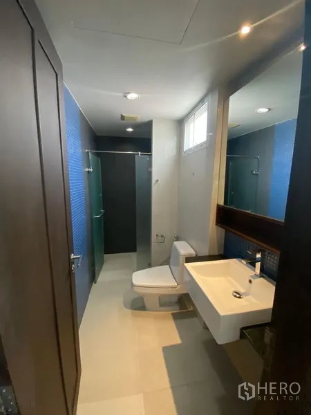 คอนโด ให้เช่าในWatthana, Bangkok - ห้องน้ำแต่งแต้มกระเบื้องสีน้ำเงิน มีห้องอาบน้ำกระจก สุขภัณฑ์ และกระจกบานใหญ่