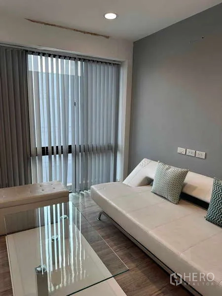 Home Office for rent in Bueng Kum, Bangkok - Cozy breakout lounge with white sofa, glass coffee table, and sliding blinds.
