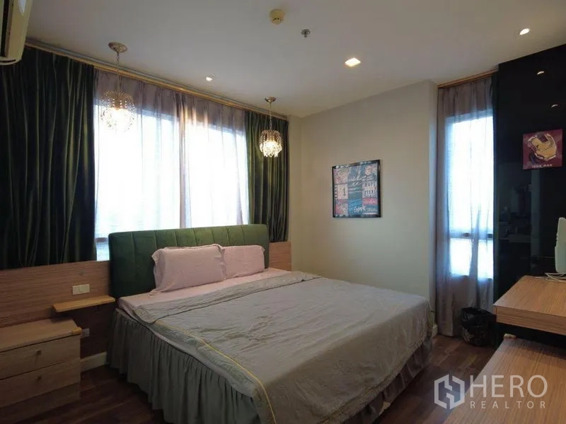Condominium for rent in Watthana, Bangkok - Master bedroom with green upholstered headboard, pendant lights and corner windows.