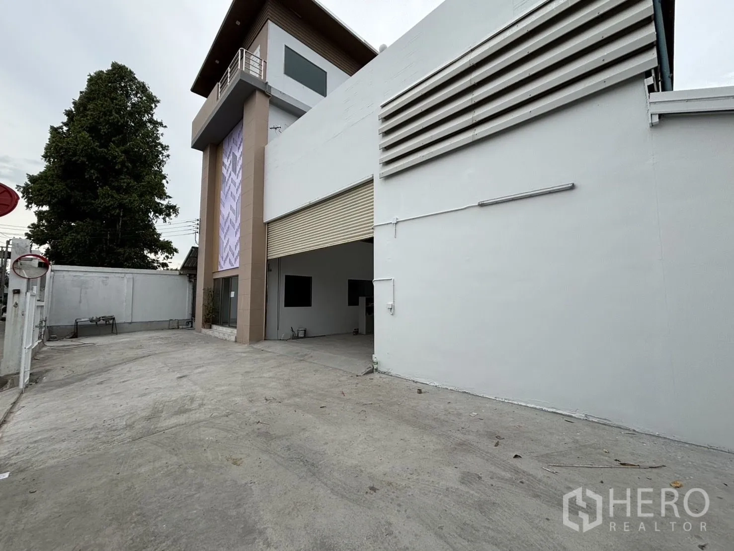 คลังสินค้า ให้เช่าหรือขายในWang Thonglang, Bangkok - ลานคอนกรีตกว้าง ประตูม้วนเชื่อมเข้าสู่โกดังและอาคารมุมสูง