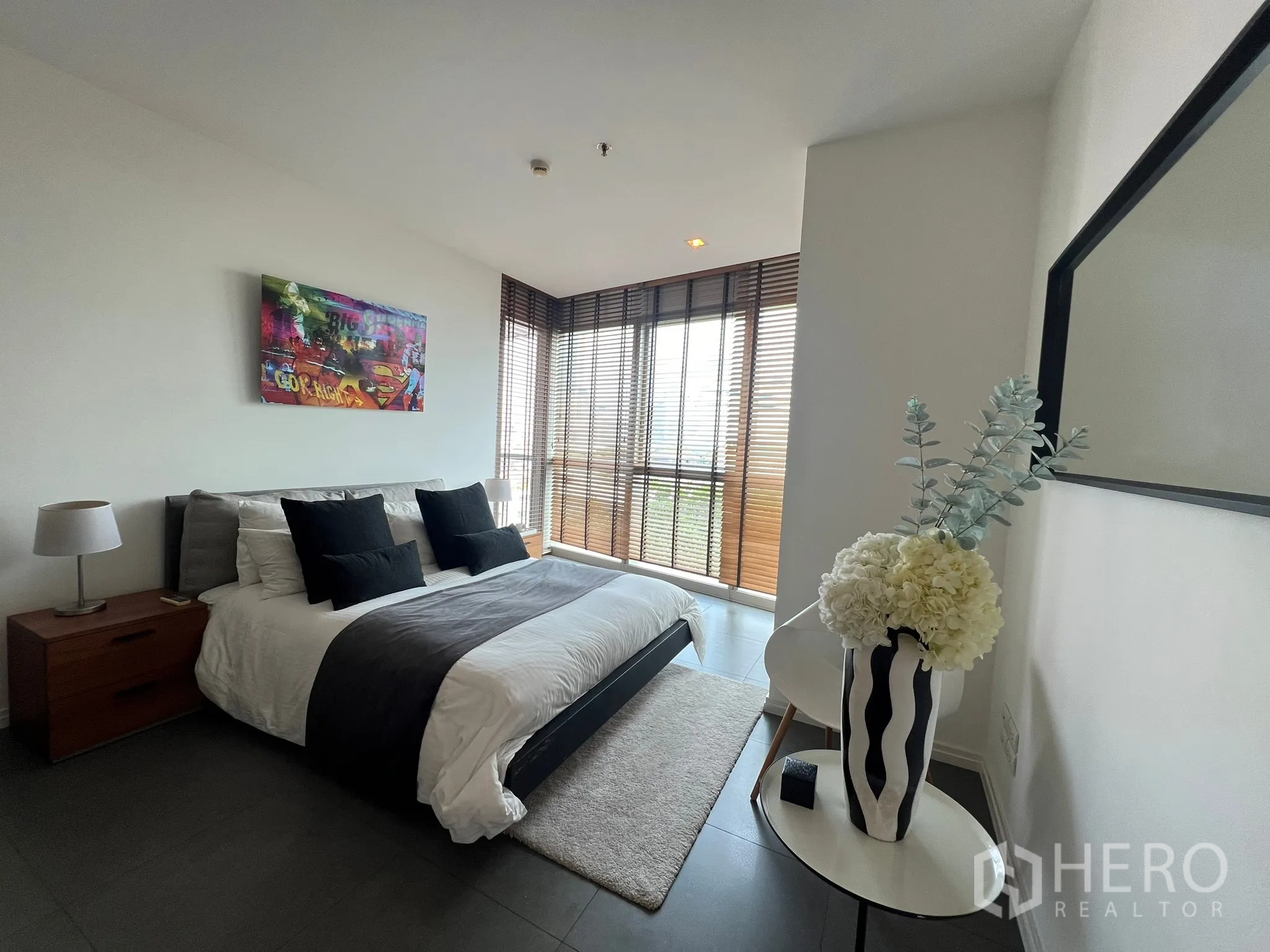 คอนโด ขายในKhlong San, Bangkok - ห้องนอนรับแสงพร้อมงานศิลป์เหนือเตียงและหน้าต่างมุมรอบด้าน