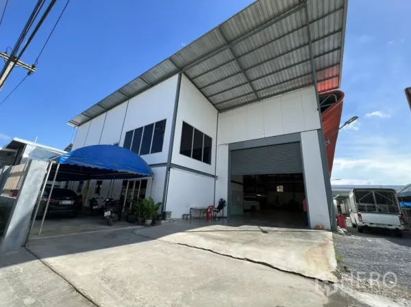 货栈 出售在Lam Luk Ka, Pathum Thani - 仓库正前方车道与加宽装卸入口，旁设蓝色雨棚停车位。