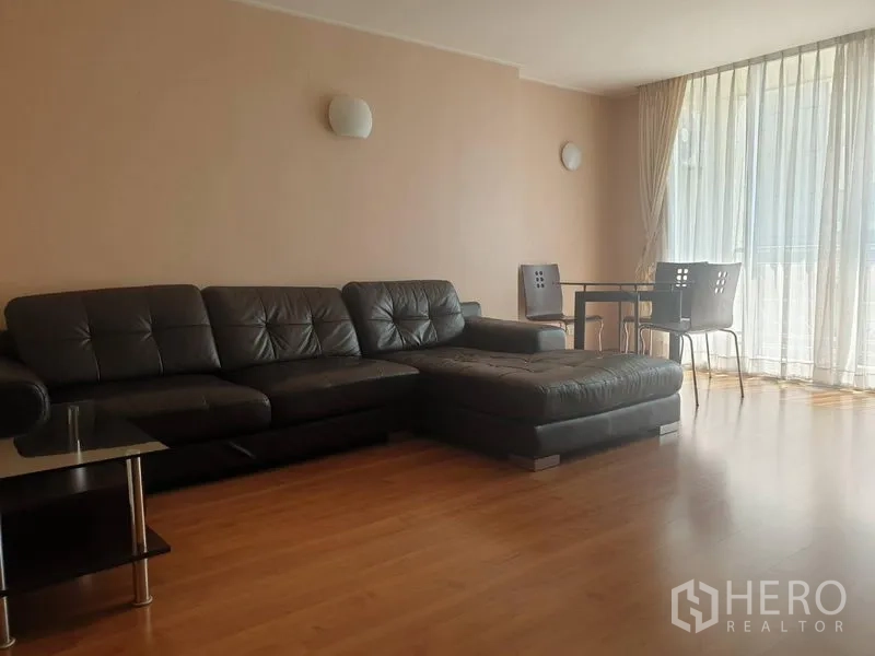 คอนโด ให้เช่าหรือขายในWatthana, Bangkok - ห้องนั่งเล่นสว่าง โซฟาหนังสีดำ มุมทานอาหาร และหน้าต่างสูงจรดเพดาน