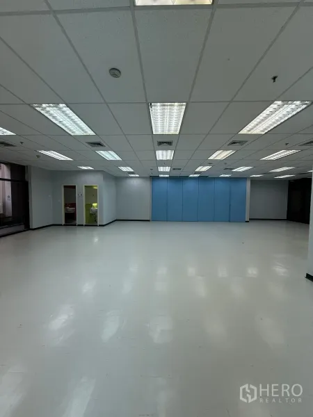 零售空间 出租在Bang Rak, Bangkok - 空置商用单元，带蓝色折叠隔断、明亮灯光与后方房间入口