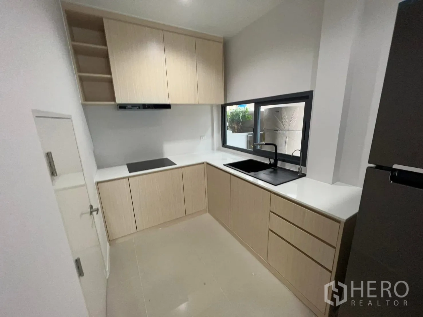 Semi-detached House for rent in Saphan Sung, Bangkok - Kitchen view showing L-shaped counters, sink beneath a window, and upper cabinets.