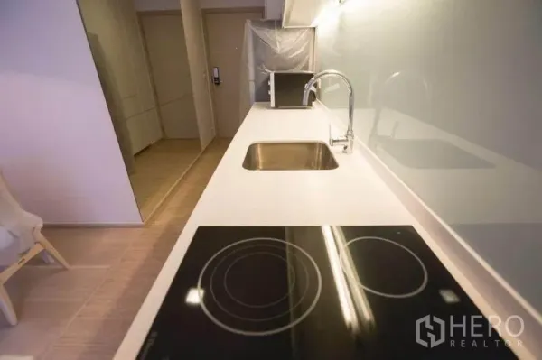 คอนโด ให้เช่าในWatthana, Bangkok - ครัวรูปตัวไอมีเตาแม่เหล็กไฟฟ้า อ่างล้างจานสแตนเลส และผนังกระจกเงา