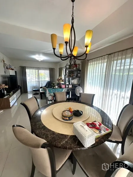 Detached House for rent in Bang Phli, Samut Prakan - Dining area with a round marble-top table, chandelier, and sliding glass doors.