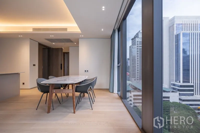 คอนโด ให้เช่าในPathum Wan, Bangkok - โต๊ะอาหารริมกระจกสูงจากพื้นจรดเพดาน มองเห็นวิวอาคารสำนักงานใจกลางเมือง