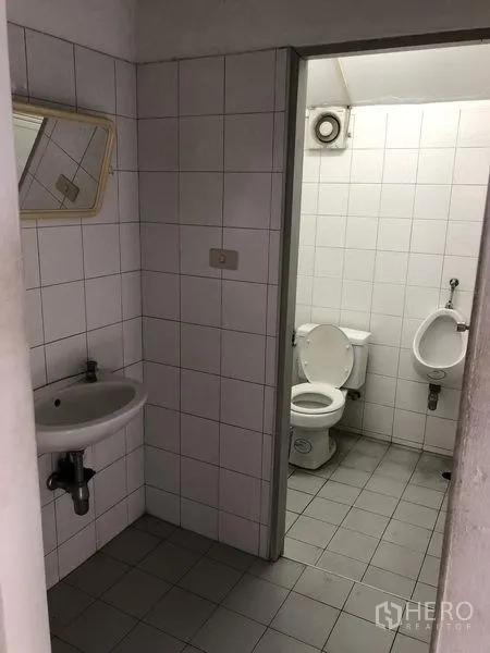Factory for rent in Pathum Thani - Ground-floor restroom with tiled walls, toilet, urinal and sink.