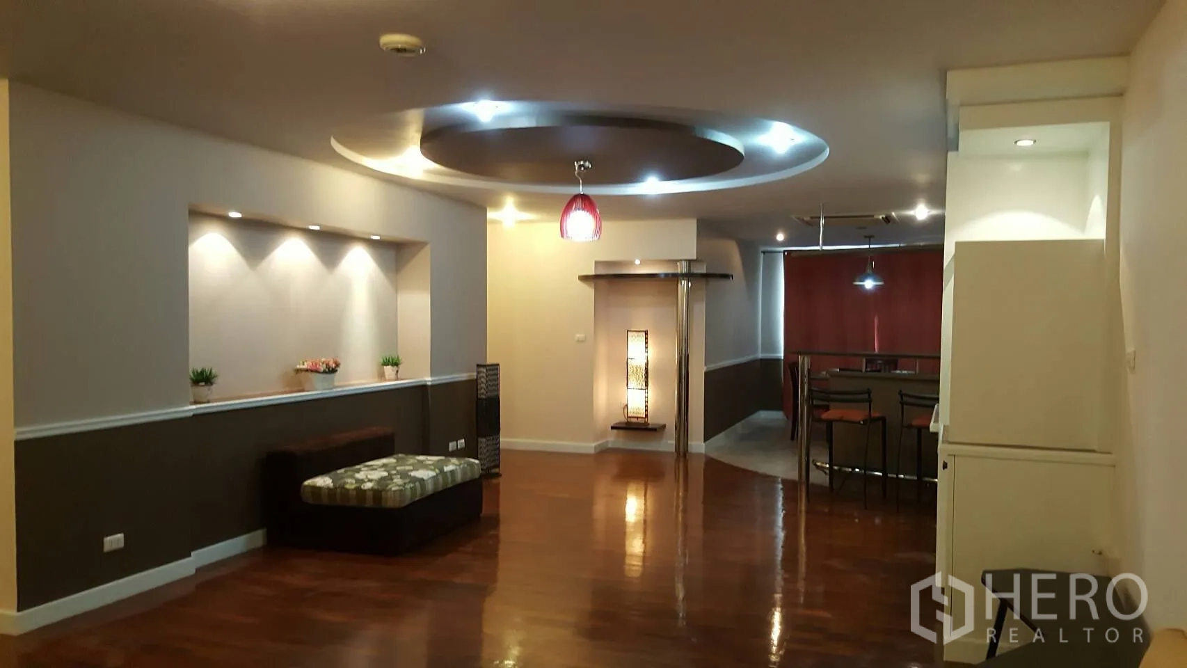 Condominium for rent in Khlong Toei, Bangkok - Spacious living area with polished wood floors, recessed wall niche and circular ceiling lighting leading to the dining zone.