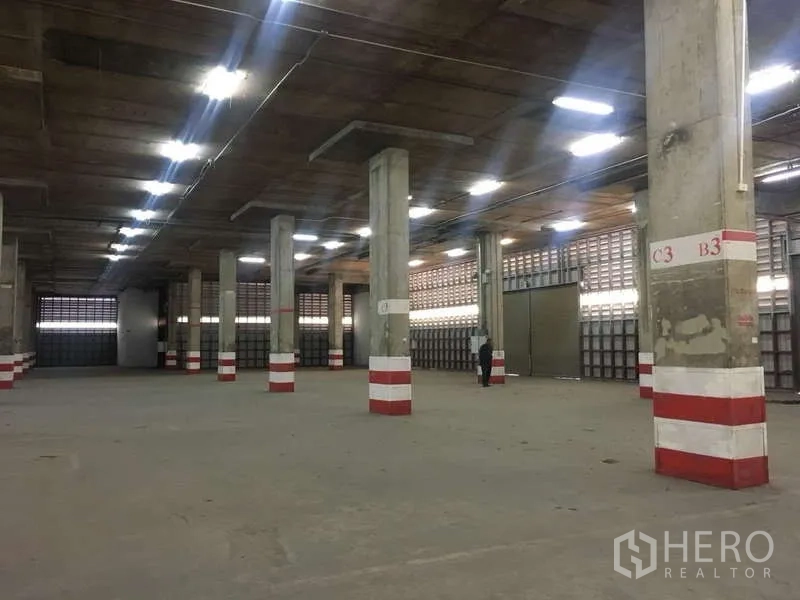 Warehouse for rent in Khlong Toei, Bangkok - Expansive warehouse floor with concrete columns, strip lighting and open storage space.