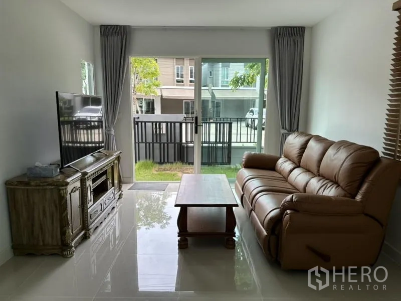 Townhouse for rent in Bang Phli, Samut Prakan - Living room with leather sofa, TV console and access to the front garden.