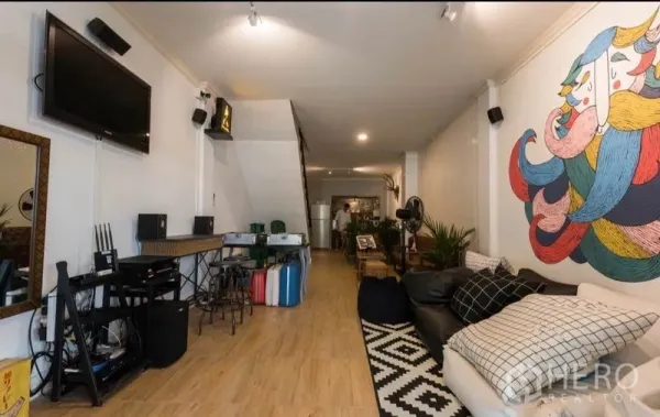 ทาวน์เฮาส์ ให้เช่าในKhlong Toei, Bangkok - ห้องนั่งเล่นแบบโอเพ่นสเปซ ปูพื้นไม้ ผนังเพนต์ลายขนาดใหญ่ ทีวีและโซฟา ในทาวน์เฮ้าส์คลองเตย