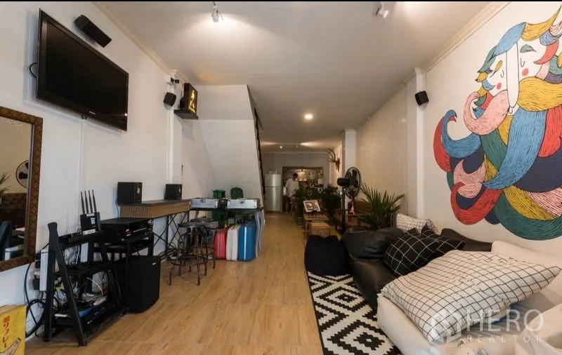 ทาวน์เฮาส์ ให้เช่าในKhlong Toei, Bangkok - ห้องนั่งเล่นแบบโอเพ่นสเปซ ปูพื้นไม้ ผนังเพนต์ลายขนาดใหญ่ ทีวีและโซฟา ในทาวน์เฮ้าส์คลองเตย