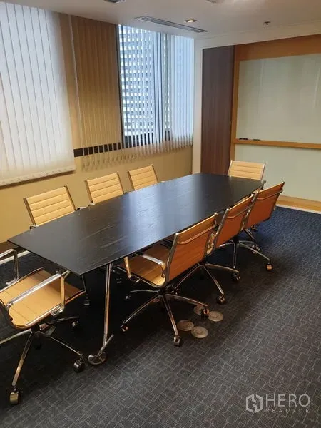 Office Space for rent - Boardroom with a long table, eight tan chairs and carpeted flooring.