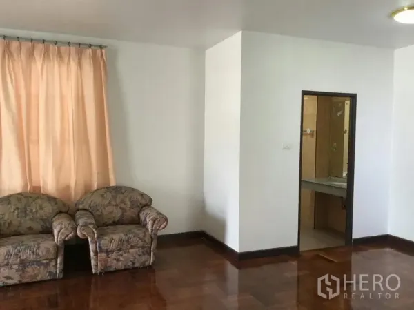 บ้าน ให้เช่าหรือขายในHuai Khwang, Bangkok - มุมนั่งเล่นพร้อมโซฟาลายดอก พื้นปาร์เกต์ และประตูทางเข้าห้องน้ำปูกระเบื้อง