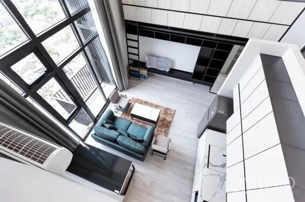 Condominium for rent in Phra Khanong, Bangkok - Double-height living room with floor-to-ceiling windows, teal sofa and built-in wall storage.