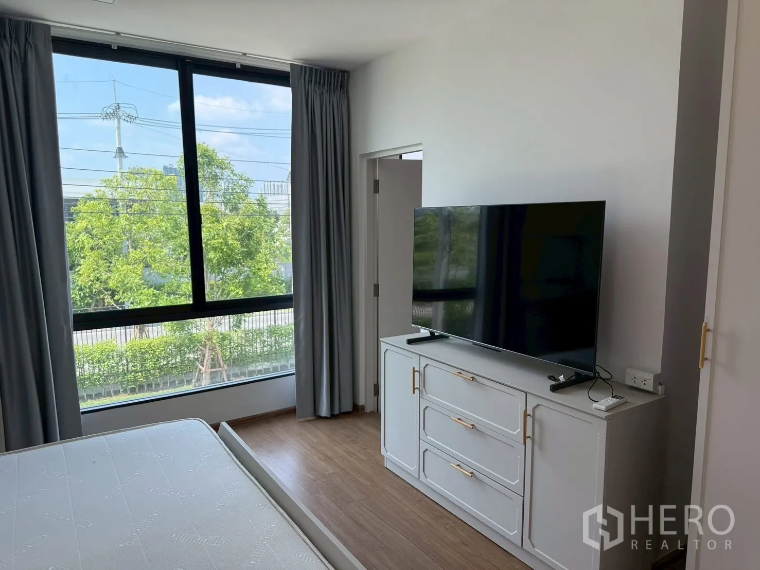 Townhouse for rent in Bang Phli, Samut Prakan - Master bedroom with large window, TV on cabinet and curtains.