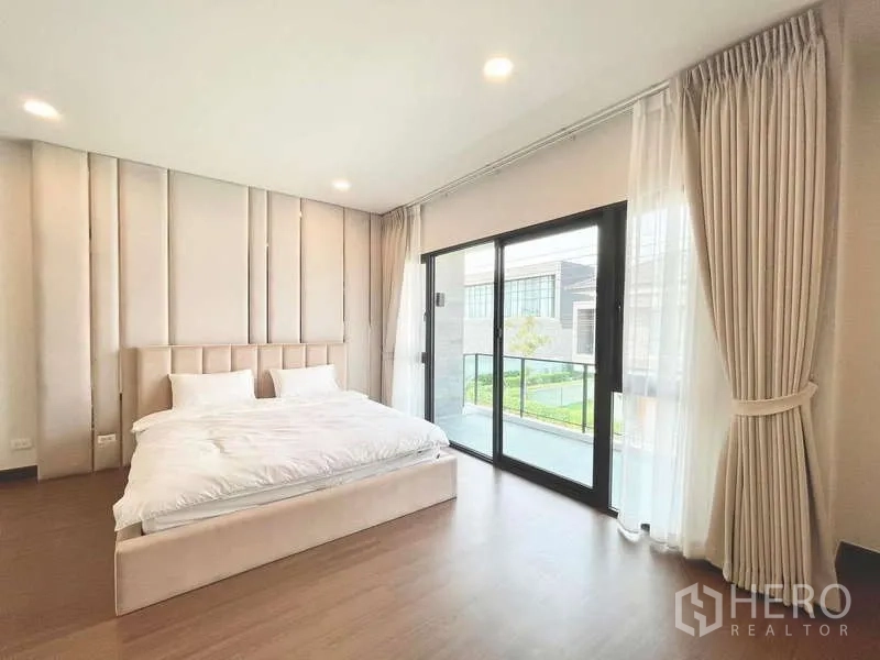 Detached House for rent in Bang Phli, Samut Prakan - Bright bedroom with sliding glass doors to a balcony overlooking the garden.